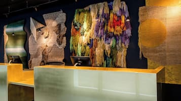 Een modern ingerichte receptie met een receptiebalie en een groot, kleurrijk wandtapijt.