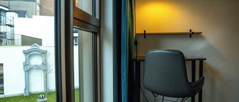A room with a view of a courtyard, a table, and a chair.
