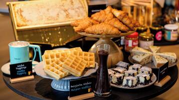 Un buffet proposant des gaufres belges, des croissants et divers desserts.