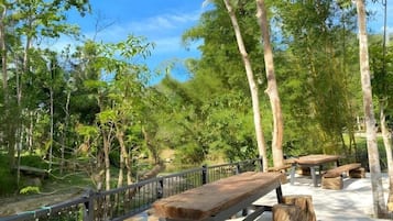 A wooden bench and picnic table set on a concrete deck surrounded by trees.