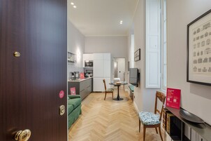Una cocina moderna con armarios blancos, un comedor con una mesa redonda y sillas, y piso de madera.