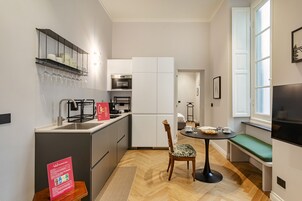Una cocina compacta con lavabo, estufa y microondas. Hay una zona de comedor con un banco y una mesa.