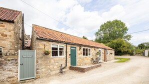 A stone cottage with a tiled roof, a gravel driveway, and a green door. - Host Stay Heather Cottage (York)