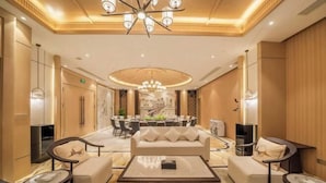 A modern hotel lobby with a central seating area, a dining table, and a chandelier. - Chinese Entrepreneur International Conference Center (Chongqing)