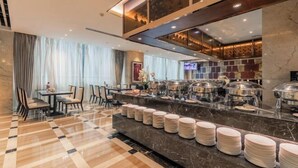A hotel lobby with a checkered floor, a buffet area with stacked plates, and a television screen. - Chinese Entrepreneur International Conference Center (Chongqing)