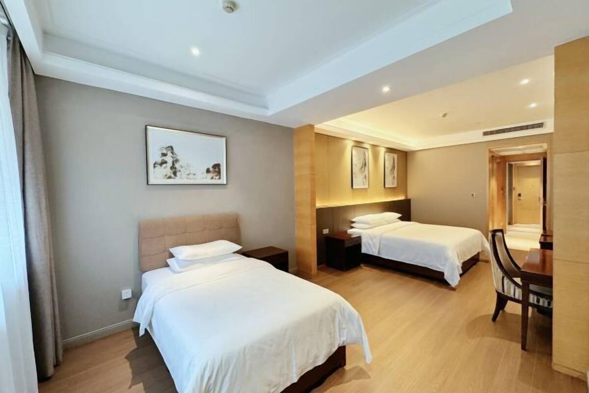 A hotel room with two beds, a desk, and a chair.