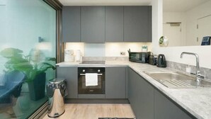 Eine moderne Küche mit grauen Schränken, einem Backofen, einer Spüle und einer Mikrowelle.
