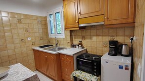 A kitchen with wooden cabinets, a sink, a stove, and a refrigerator. - Grandma’s Pine Apartments – Cozy Double Bed (Paralia Politikon)