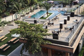 A rooftop pool area with lounge chairs, tables, and a small pool.