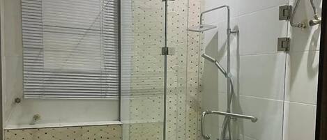 A modern bathroom with a glass-enclosed shower, a toilet, and a window.