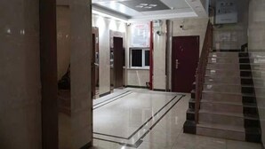 Eine Hotelhalle mit Marmorboden, einer Treppe und einer roten Tür.