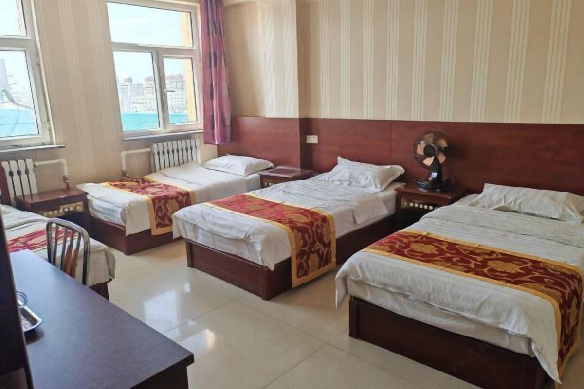 Habitación de hotel con tres camas, un escritorio y una silla.