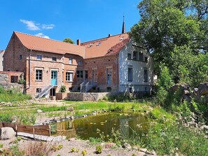 A historic building with a brick facade, a small pond, and a staircase leading to the entrance. - Kranichhof Mescherin (Mescherin)
