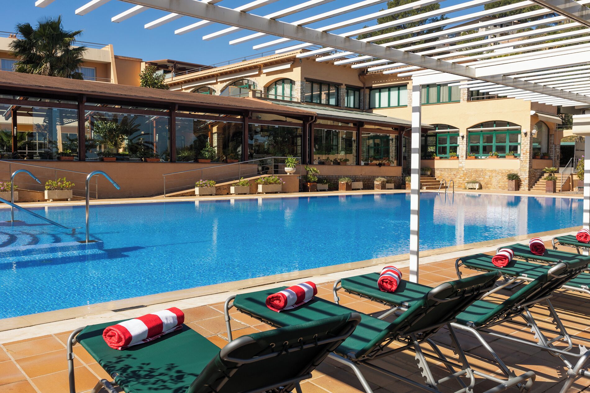 Una piscina con sillas de descanso y una pérgola.