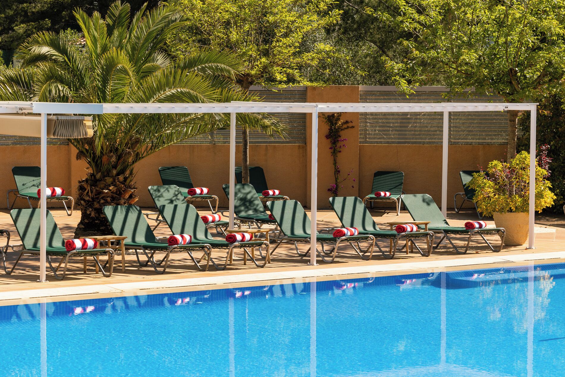 A poolside area with lounge chairs and a covered seating area.