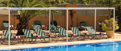 A poolside area with lounge chairs and a covered seating area.