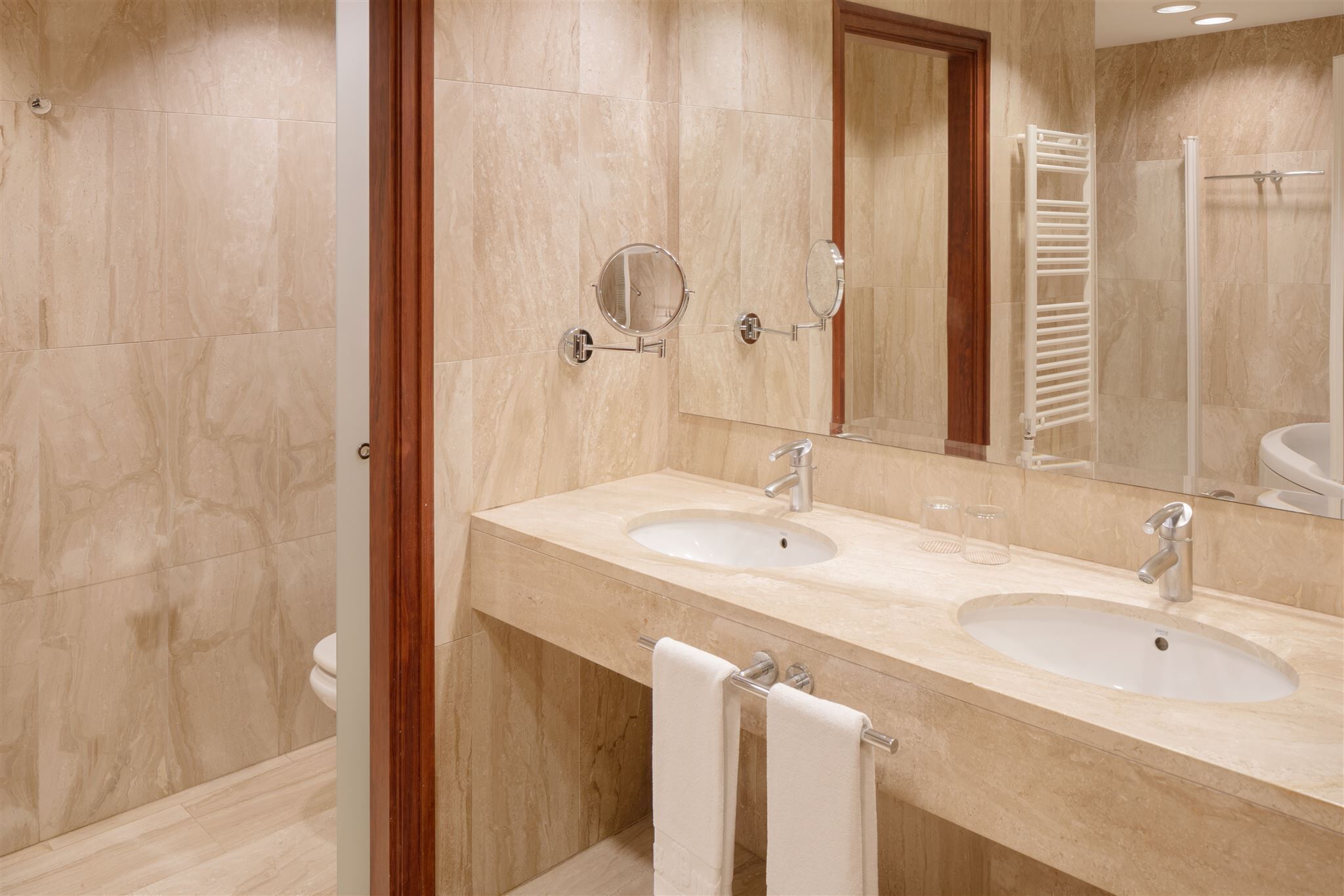 A bathroom with two sinks, a mirror, and a towel rack.