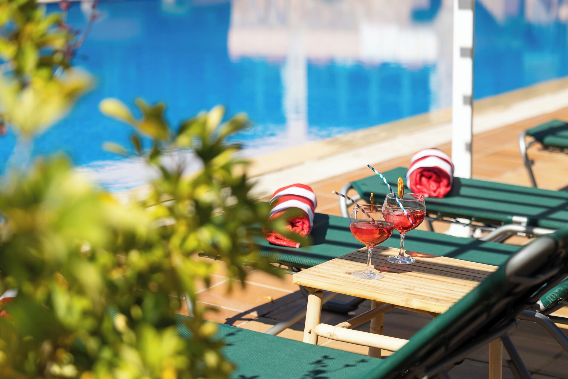 A poolside area with lounge chairs and a table with drinks.