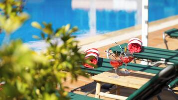 A poolside area with lounge chairs and a table with drinks.