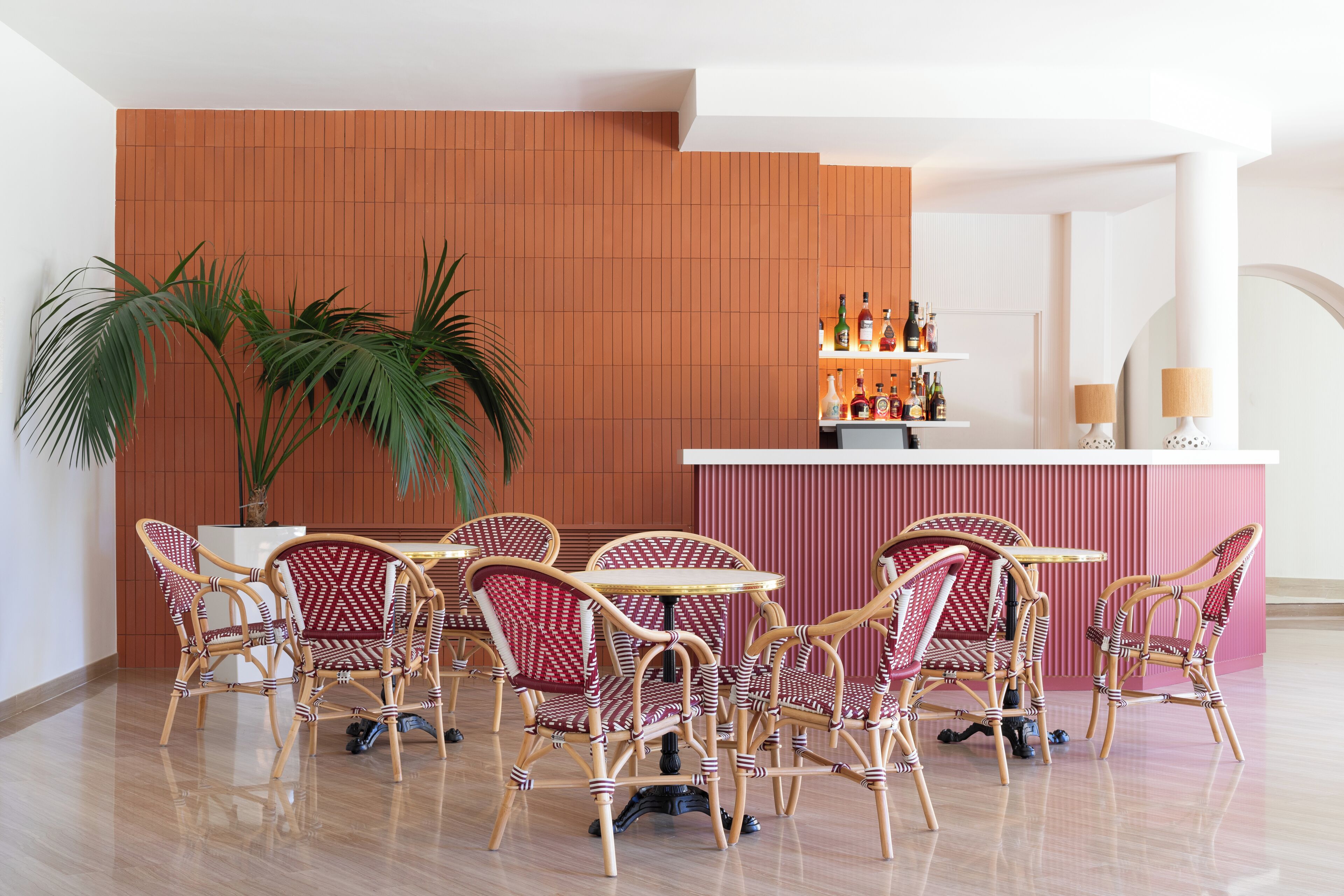 Une pièce avec des chaises en osier et un coin bar avec des bouteilles.