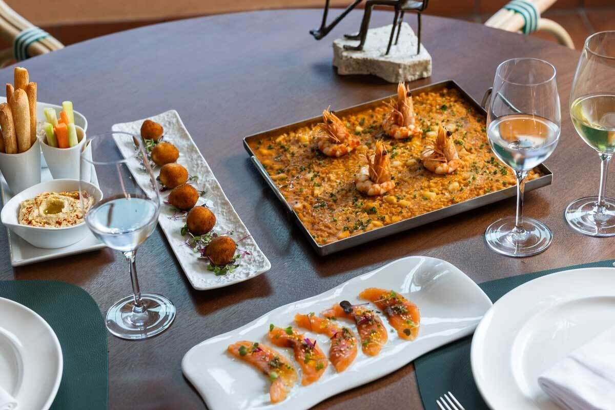 A dining table with seafood dishes, including shrimp, bread, and croquettes.