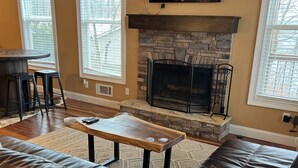 A living room with a stone fireplace, leather sofa, and a TV mounted above it.