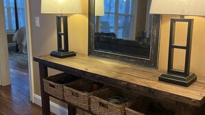 A wooden console table with two wall-mounted lamps and a mirror.