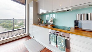 A modern kitchen with a large window, stainless steel appliances, and a view of the city. - Basildon - 2 Bed Flat - Sleeps 5 - Near Station (Basildon)