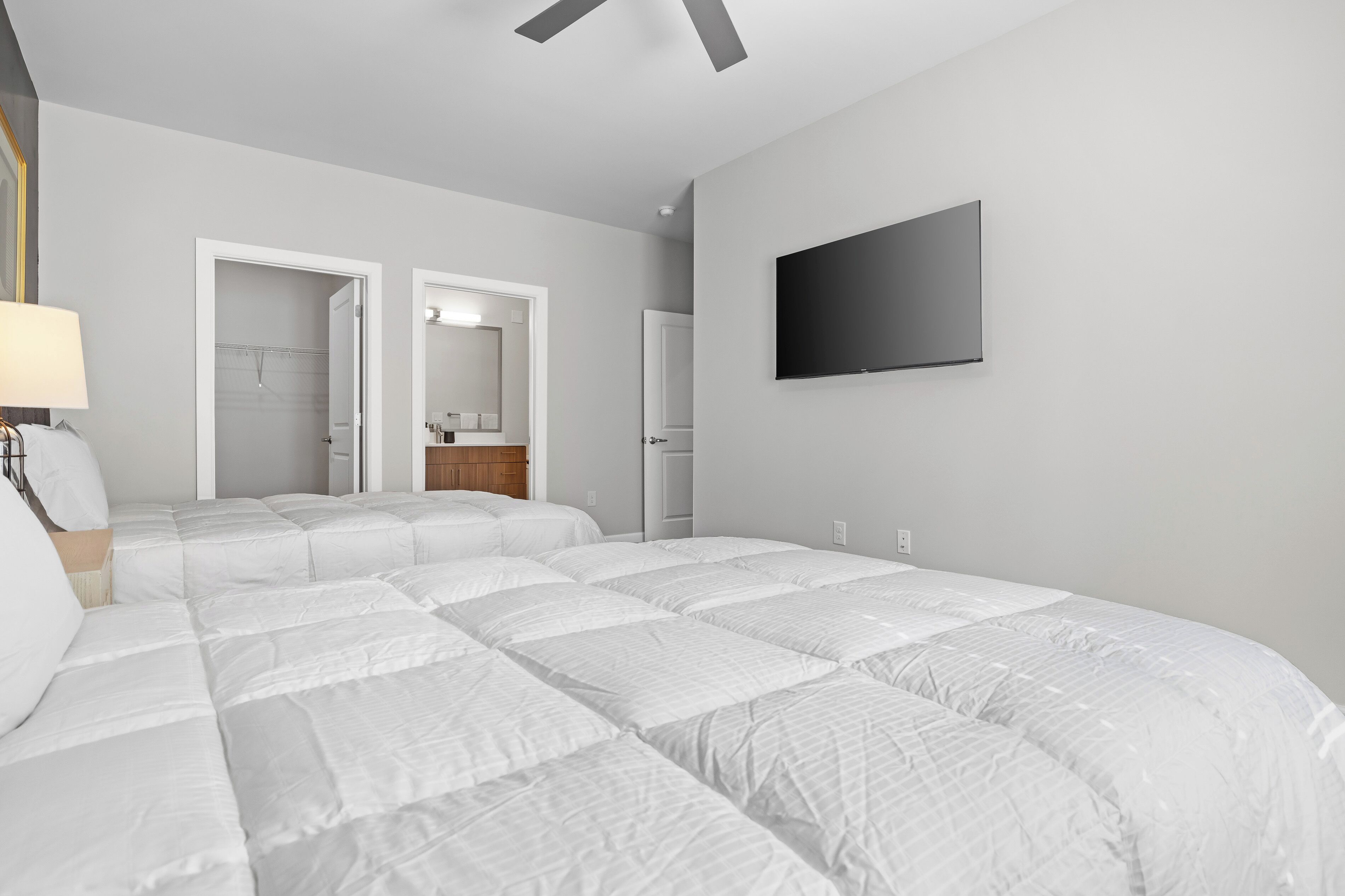 Un dormitorio moderno con una cama grande, un televisor de pantalla plana y un vestidor.
