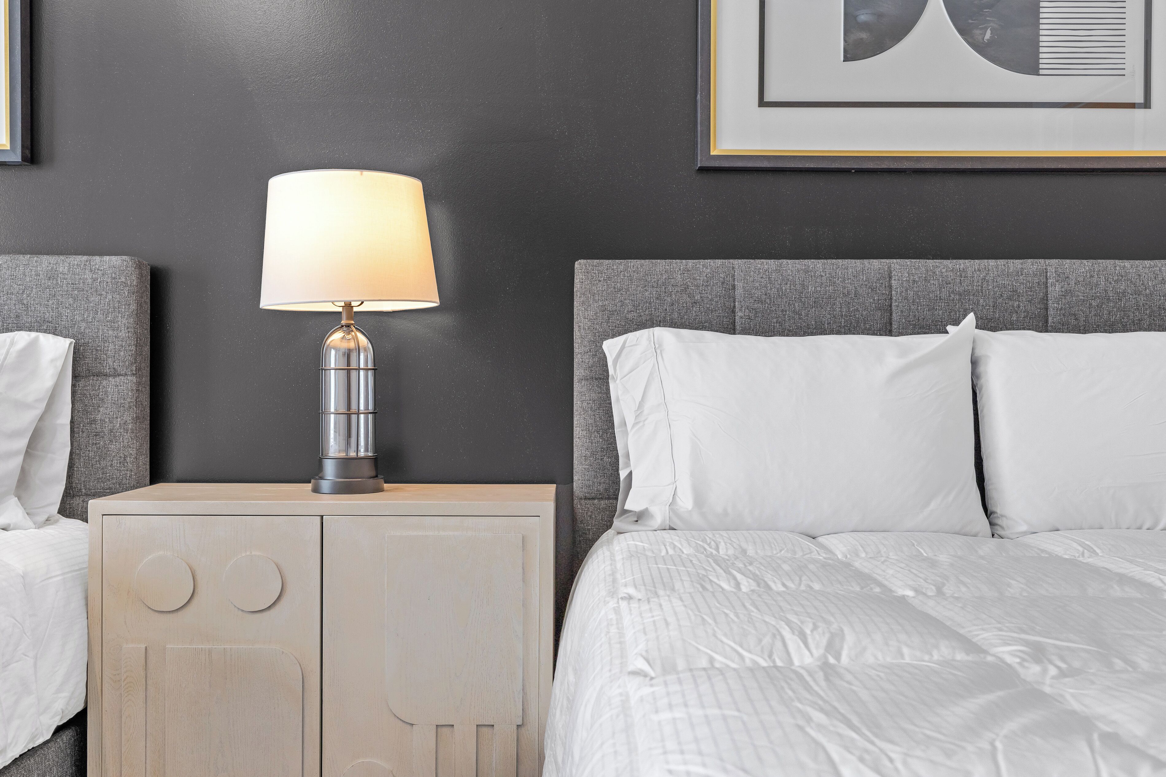 Une chambre d’hôtel avec un lit, une table de chevet avec une lampe et un mur orné de tableaux.