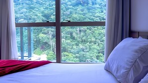 Une chambre à coucher dotée d’une grande fenêtre donnant sur une forêt dense.