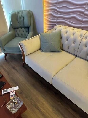 Relax in this stylish living room with a tufted sofa, matching armchair, and decorative wall panel.