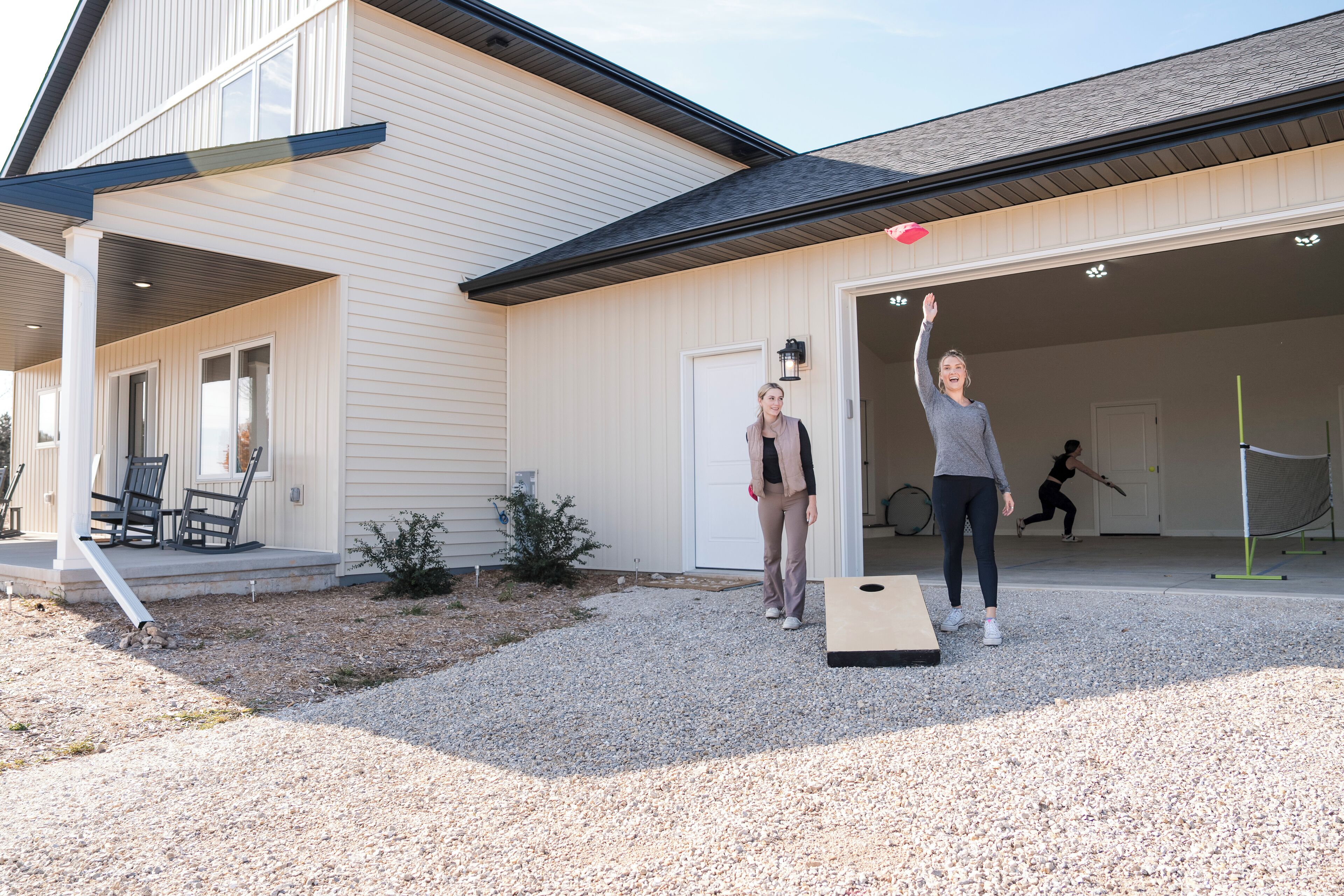 A house with a covered porch, a garage, and a gravel driveway.