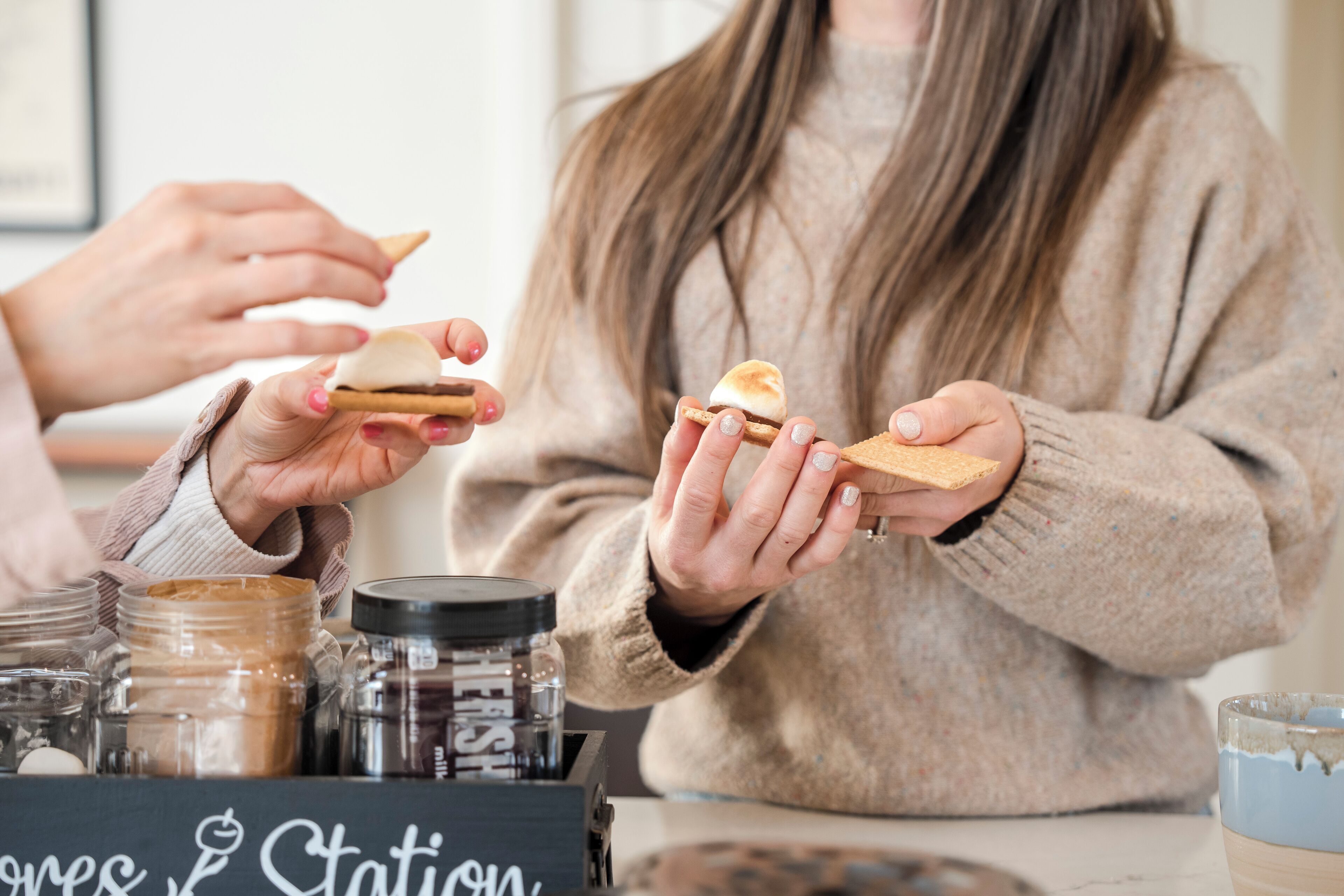 A person holding a s'more with marshmallows and graham crackers.