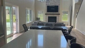 Una cocina amplia con una isla grande, una chimenea de piedra y un televisor montado en la pared.