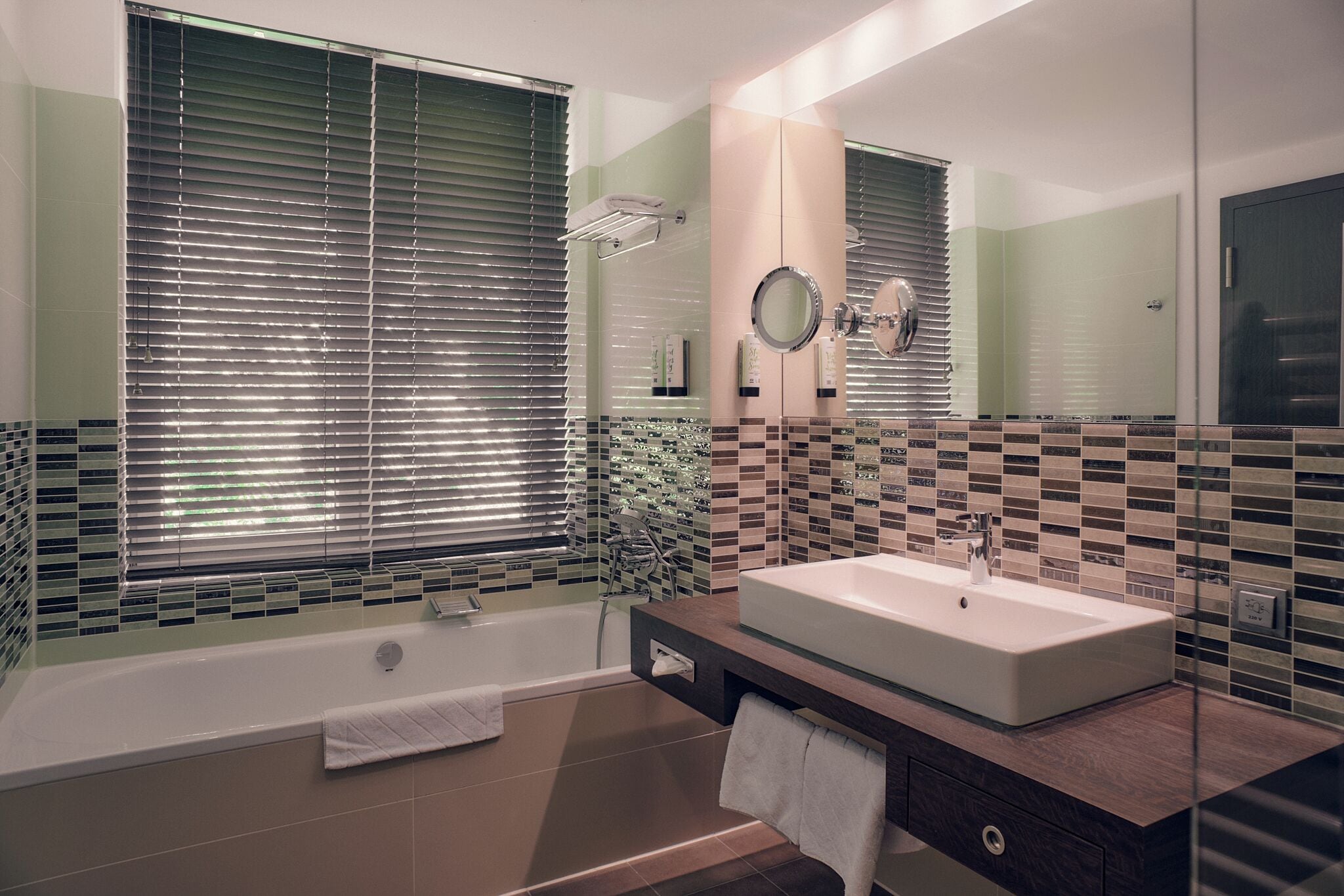 A modern bathroom with a large bathtub, a vanity with a mirror, and a tiled backsplash.