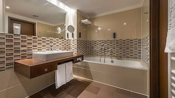Een moderne badkamer met een groot bad, een wastafel met spiegel en een betegelde spatwand.