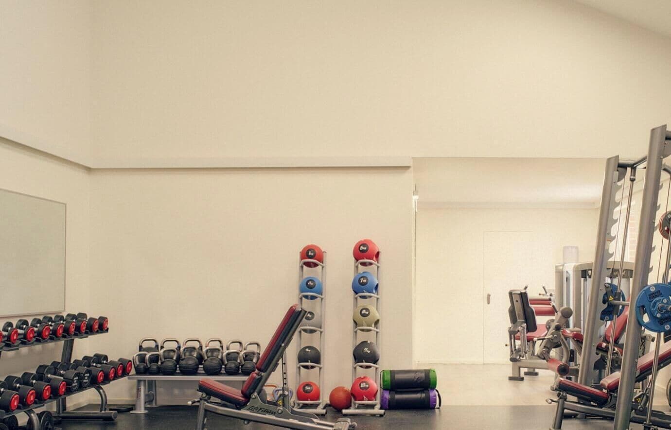 Ein Fitnessstudio mit Gewichten, Kettlebells und Trainingsgeräten.