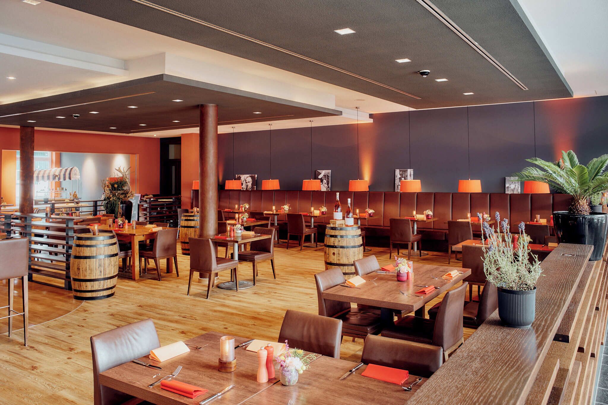 A modern restaurant with wooden tables, chairs, and a bar area.