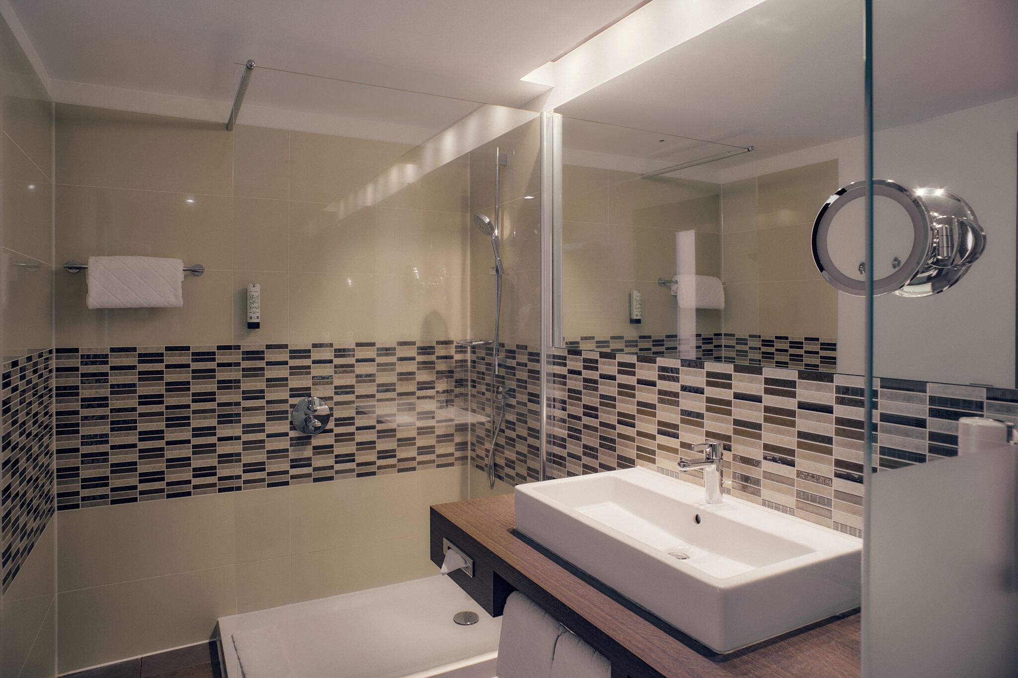A modern bathroom with a glass-enclosed shower, a white sink, and a mirror with a circular frame.