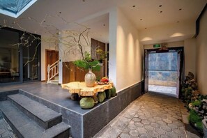 A hotel lobby with a reception desk, a staircase, and a view of the outside. - Guanhai Yayuan (Dali City)