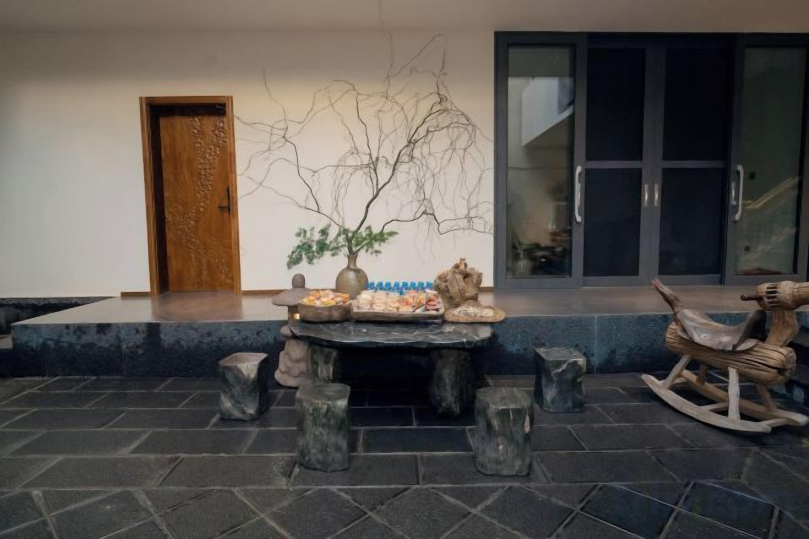 Un área de estar al aire libre con una mesa, sillas y una escultura rocosa decorativa.