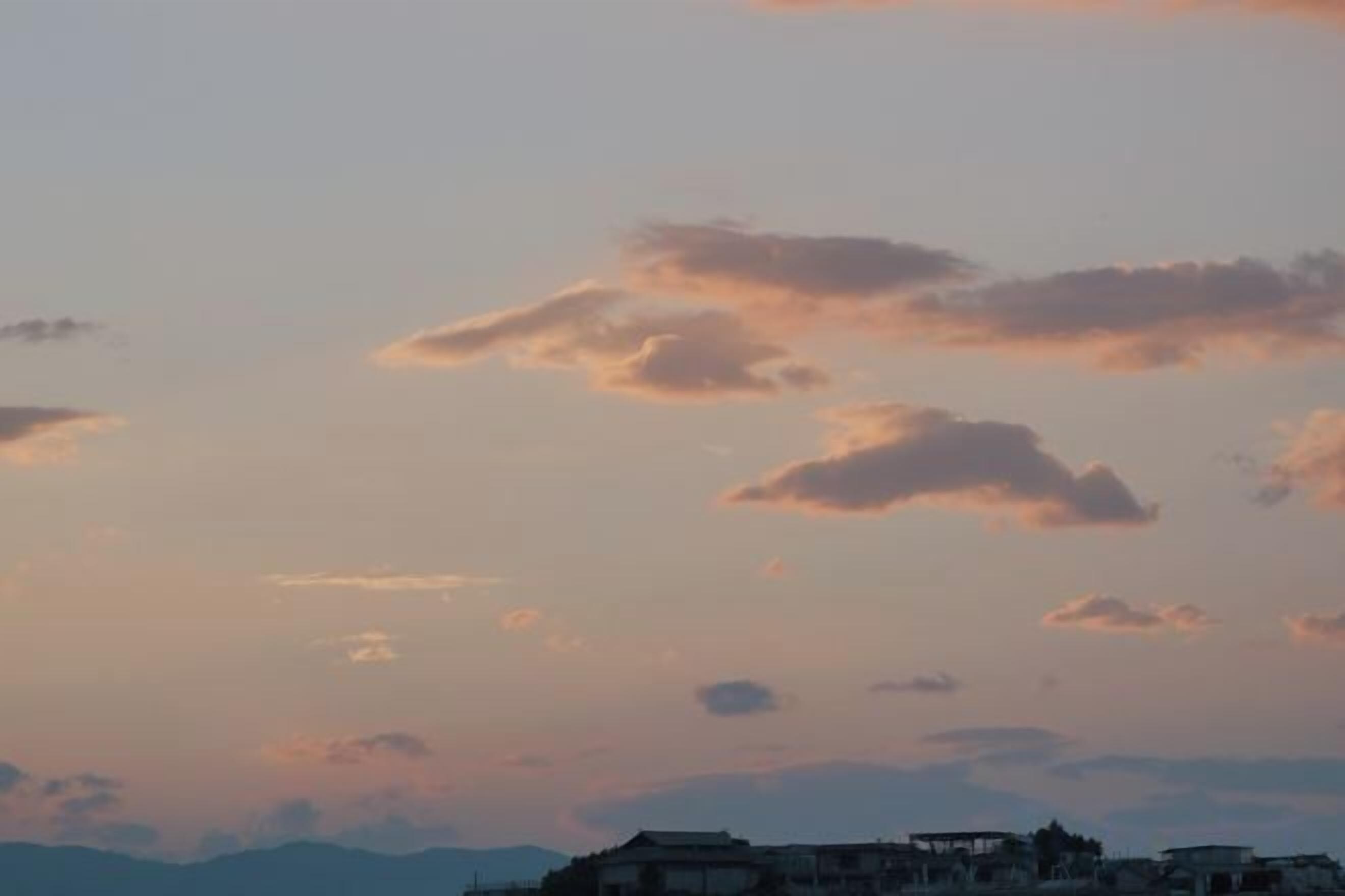 Un atardecer con nubes y una vista distante de edificios.