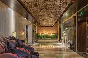 Hall d'albergo con soffitto decorato, una reception e una parete con piante verticali.