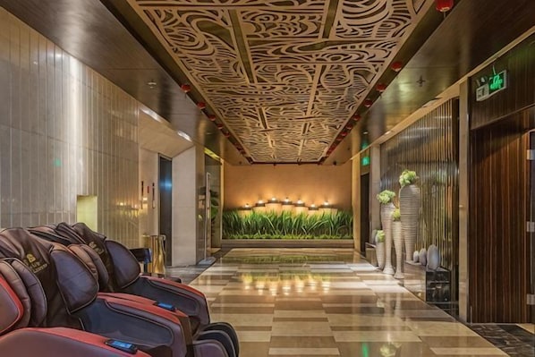 A hotel lobby with a patterned ceiling, a reception desk, and a wall with vertical plants. - Huasheng Hotel (Shanyin)