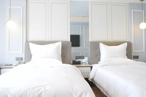 Ein Hotelzimmer mit zwei Betten, einem Schreibtisch und einem Fernseher.