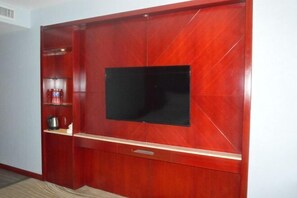 Ein Holzunterhaltungsschrank mit einem Flachbildfernseher, Regalen mit Gegenständen und einer Schublade unter dem Fernseher.