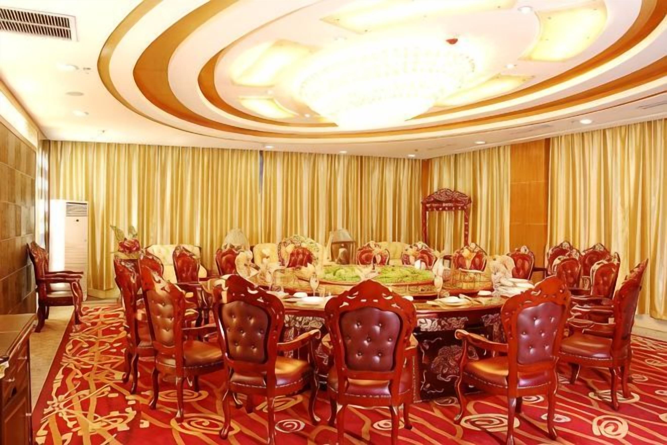 A formal dining room with a large round table, multiple chairs, and a chandelier.