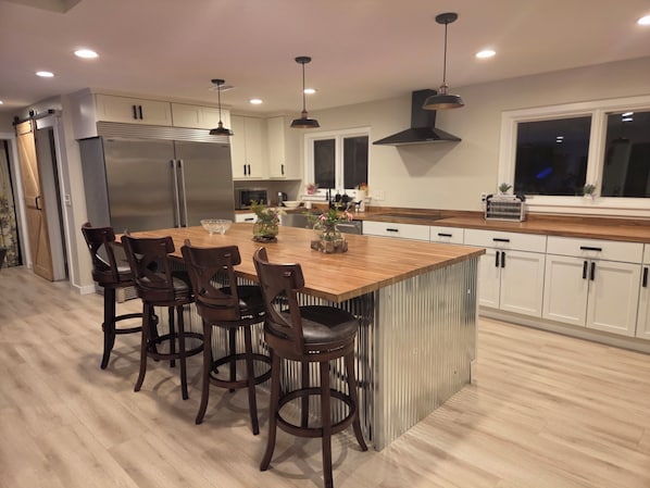A modern kitchen with a central island, wooden chairs, stainless steel appliances, and pendant lighting. - Charming 4-bedroomHorse Ranch farmhouse in enjoyable Lebanon with AC, Wifi (Lebanon)
