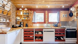 A compact kitchen with wooden cabinets, a built-in oven, and a brick floor. - 6 Person Holiday Home in Blokhus (Blokhus)